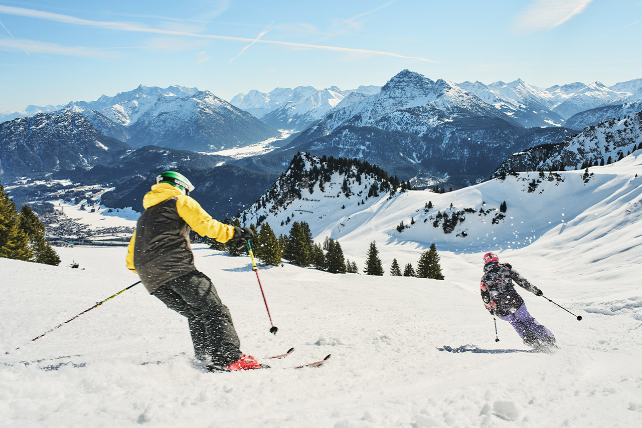 Zwei Menschen, die eine Skipiste hinunterfahren.