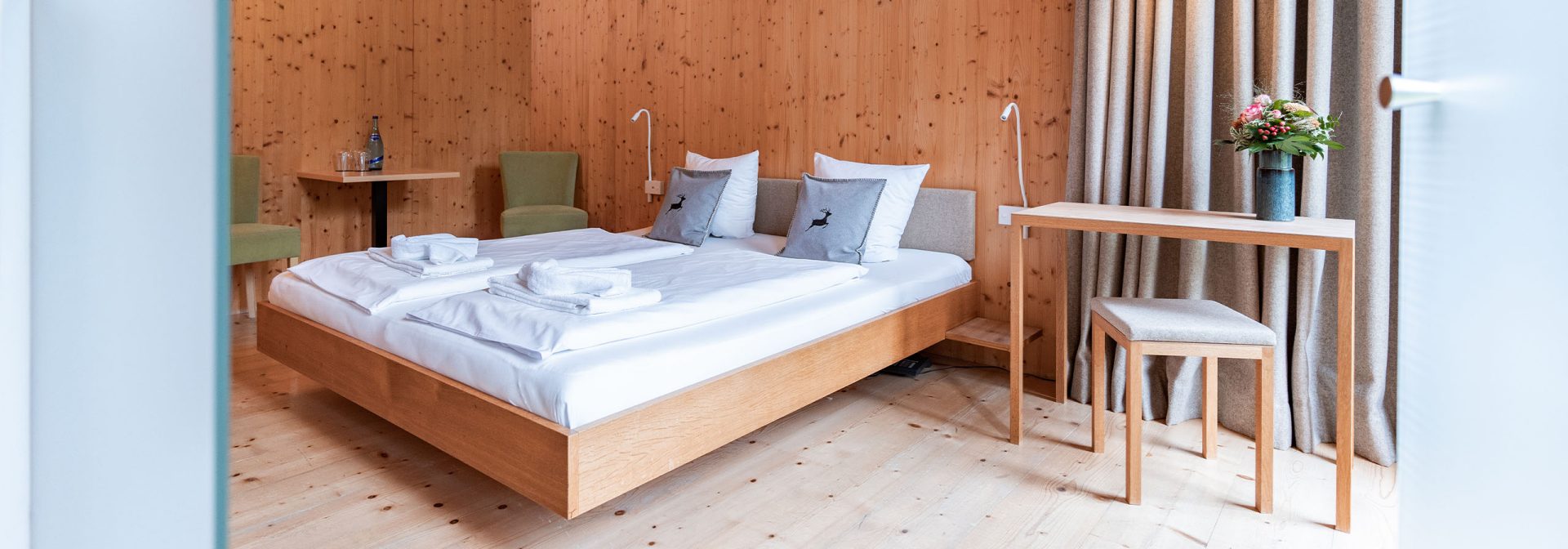 Innenansicht eines Holzverkleideten Zimmers des Alpenhotel Ammerwald. 