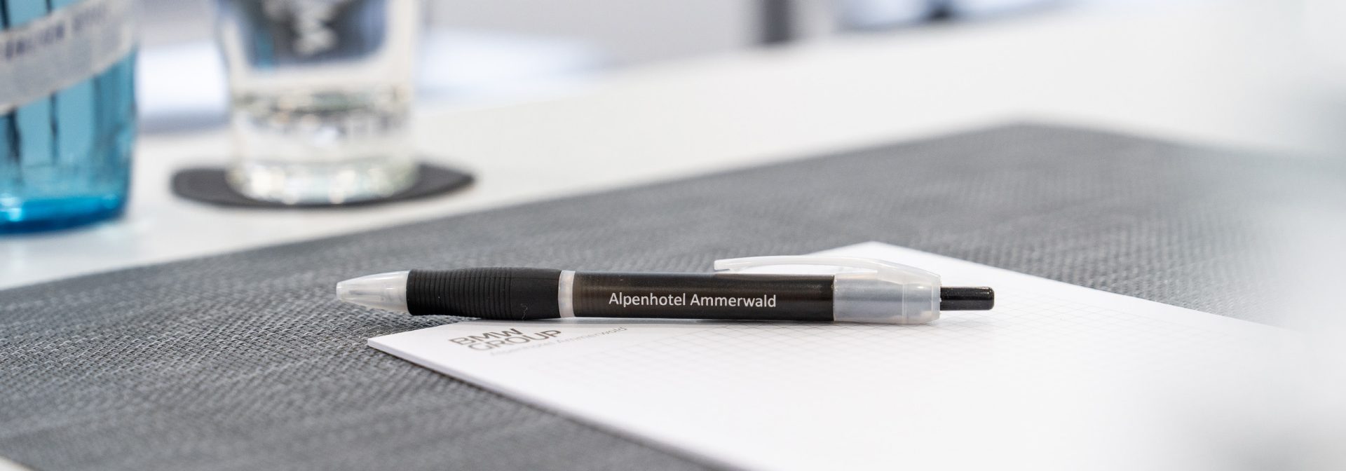 Ein Kugelschreiber mit der Aufschrift “Alpenhotel Ammerwald” liegt auf einem Block.